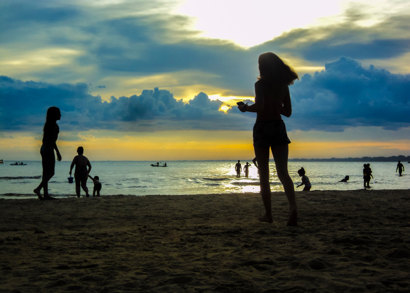 CANELONES, URUGUAY, FEBRAURY - 2015 - Group of people silhouettes at the beach with the sunset at the background