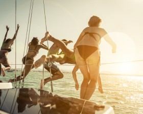 group of friends jumping in the water from the boat during an excursion. concept about vacations,leisure and fun