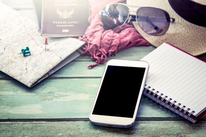 Preparation for travel, cellphone, sunglasses ,passport, road map,hat and notebook on wooden table in vintage filter