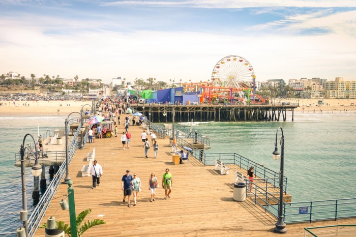 Santa Monica, CA, USA - March 18, 2015: high angle view of international tourists and local people at Santa Monica Pier with ferris wheel of Pacific Amusement Park - Famous american landmark on californian coast