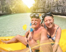 Senior happy couple taking selfie on kayak at Big Lagoon in El Nido Palawan - Travel to Philippines wonders - Active elderly concept around the world - Lens flare and sun halo are part of composition