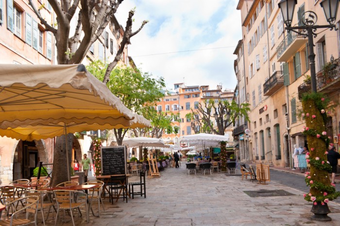 Grasse, France - May 8, 2013: Early in the morning just opened cafes on the town square (Place aux Aires), and tourists walking and looking for suitable one.