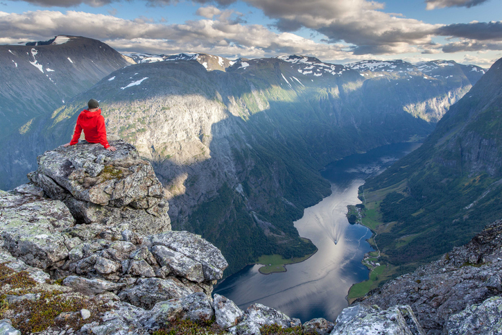Man rests above Naeroyfjord and enjoys the view from Breiskrednosi, Norway