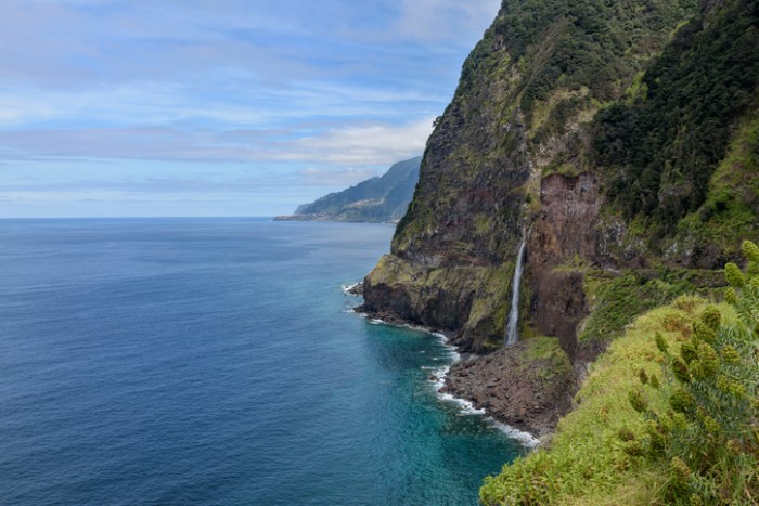 Landscape with volcanic cliffs and the"Bridal Veil" waterfall over old, abandoned road, Seixal, North coast of Madeira, Portugal