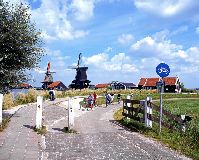 Zaanse Schans, The Netherlands - July 30, 1997: Row of windmills along the banks of the river Zaan with a cyclists in the foreground, Zaanse Schans, Holland, Netherlands, Europe.