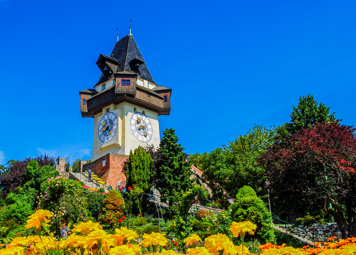 clock tower and beautiful flowers in garden on hill, Graz, Austria