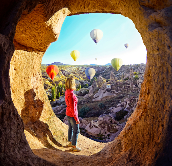 Woman watching  like colorful hot air balloons flying over the valley at Cappadocia, Turkey. Volcanic mountains in Goreme national park.