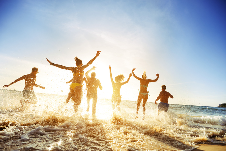 Crowd of people or friends runs to sunset sea. Beach holidays travel concept