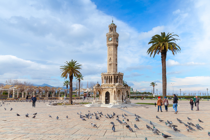 Izmir, Turkey - February 12, 2015: Doves and walking people on Konak Square near the historical clock tower