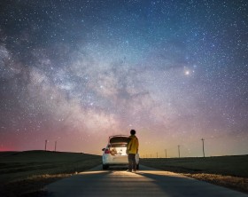 Rear view of one man glaring at the palette of milky way with car trunk open