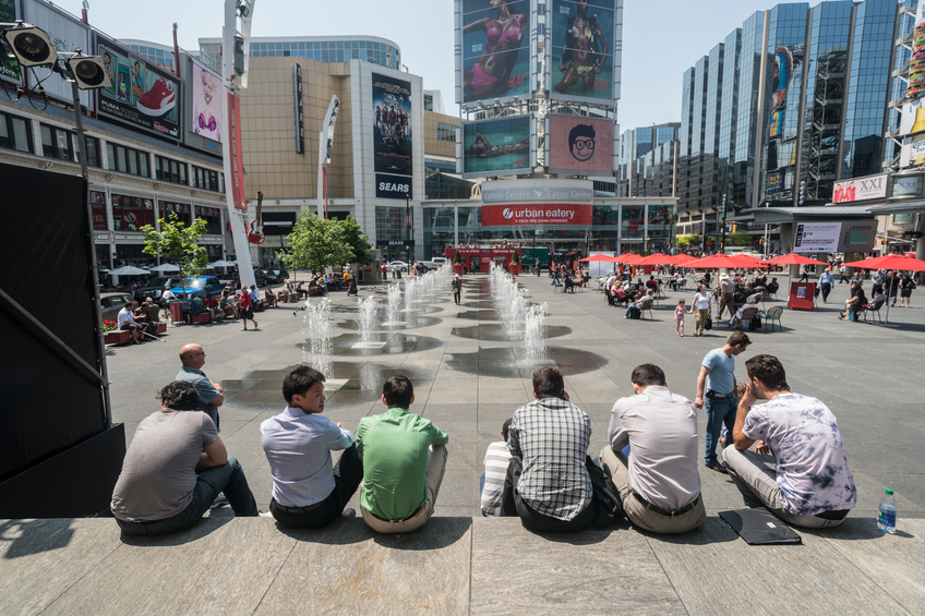 "Toronto, Canada - May 23, 2012: A group of friends sits on the stage area of Dundas Square on a hot May afternoon."