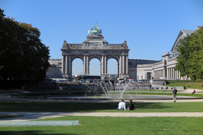 Brussels, Belgium - October 2, 2015:  A couple sits before the fountain and arch in the Parc du Cinquantenaire.  The park and arch, which wasn't completed until 1905, were built to celebrate the Golden Jubilee of Belgian independence in 1880.