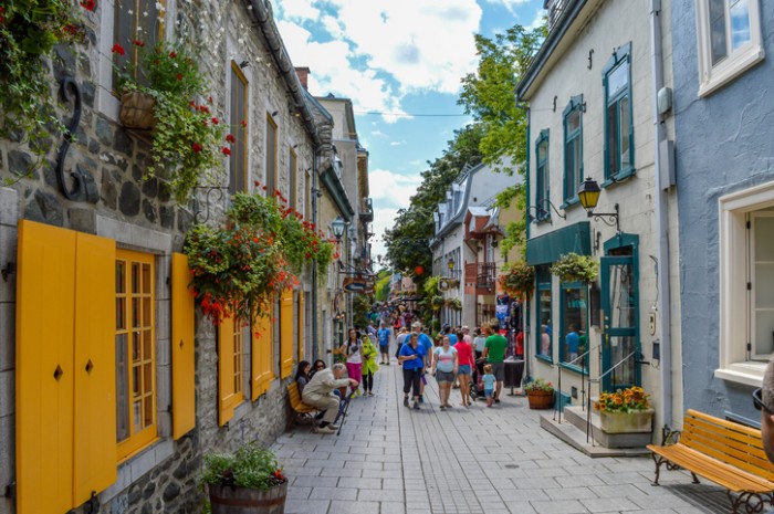 Quebec City, QC, Canada - 01 August, 2015: An elderly man stands up from the bench while other tourists are walking on the pedestrian street.