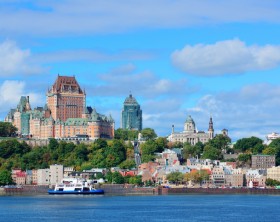 Quebec City skyline over river with blue sky and cloud.