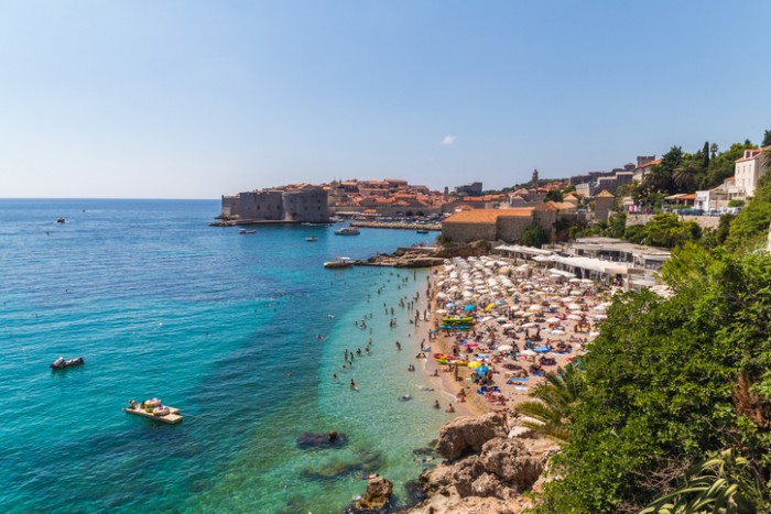 Dubrovnik, Croatia - August 10, 2016: A view of Banje Beach, the Adriatic Sea and Old Town in Dubrovnik during the day in the summer. Large amounts of people can be seen.