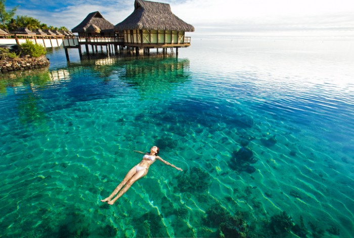 Young woman in white bikini swimming in a coral lagoon