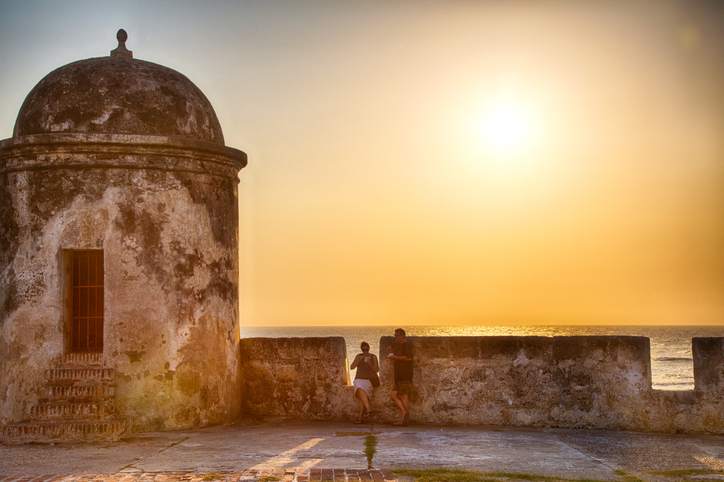 Cartagena, Colombia - February 24, 2014: Tourists and local residents watch the sun set over the caribbean sea from the old city wall surrounding Cartagena.