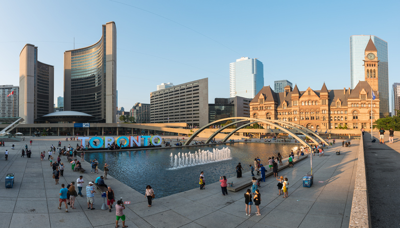 Toronto, Canada - September 6, 2015: Panorama view of Nathan Phillips Square in Toronto bustling with locals and tourists on a clear sunny afternoon, with the Toronto sign and the new and old City Halls in the background.