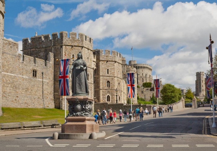 Windsor, United Kingdom - August 28, 2012: View of Windsor Castle, which is official residence of royal British family in Berkshire with Queen Victoria Statue on the foreground and the flow of tourists