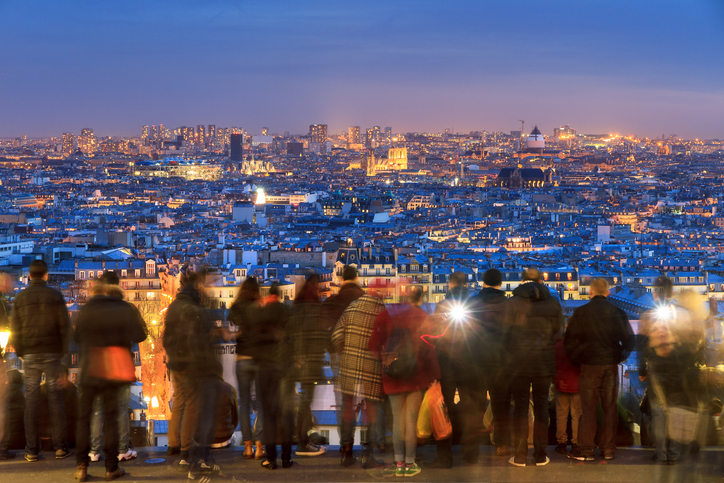 People looking at the beautiful skyline of Paris from Montmartre at night