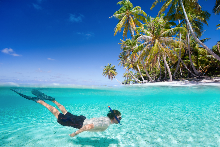Man swimming in a clear tropical waters in front of exotic island
