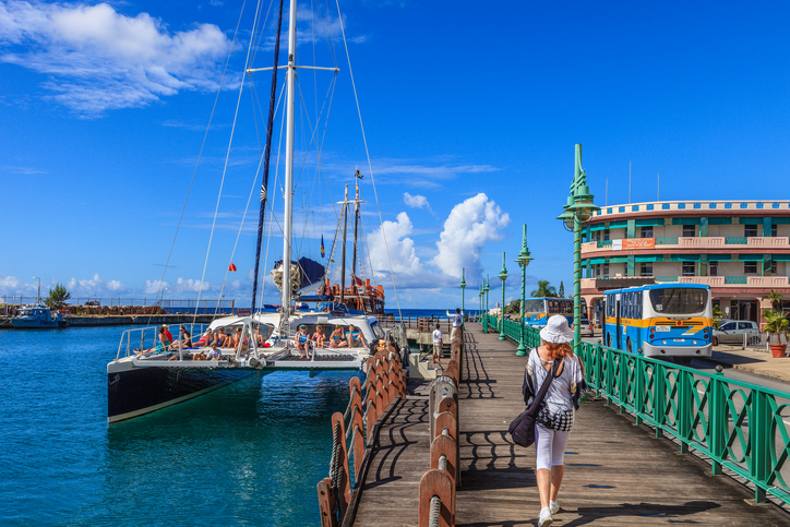 Bridgetown, Barbados - November 20, 2011: a catamaran with tourists on board is waiting to weigh anchor for a traditional excursion by sea. People are walking on the wharf located in the city downtown.