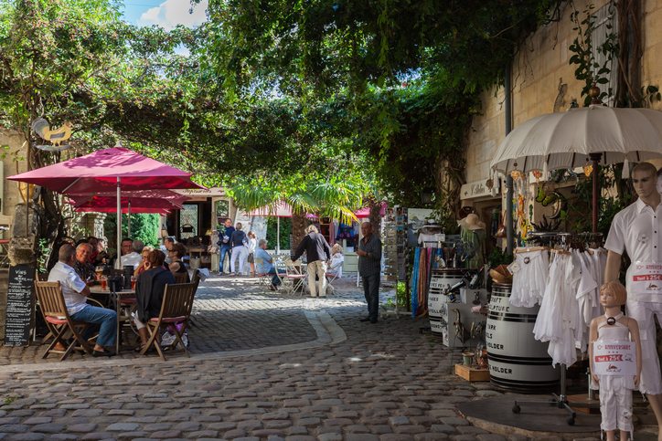 Saint Emilion, France – August 31, 2012: St. Emilion square with cafes and shops for tourists. Tourists rest at the tables of street cafe