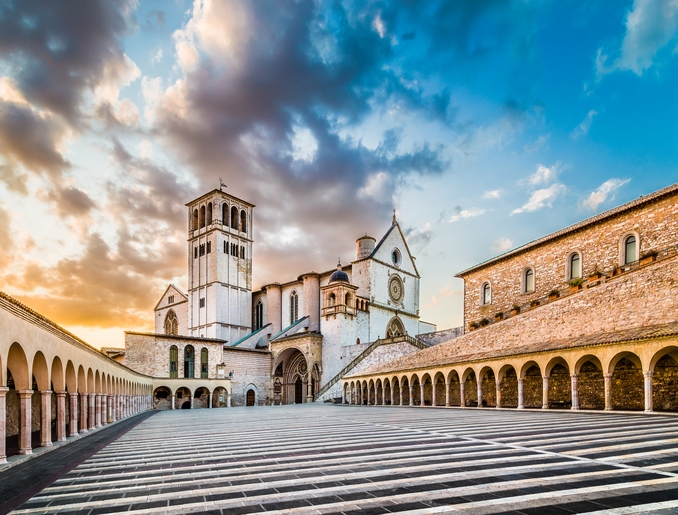 Famous Basilica of St. Francis of Assisi (Basilica Papale di San Francesco) with Lower Plaza at sunset in Assisi, Umbria, Italy.