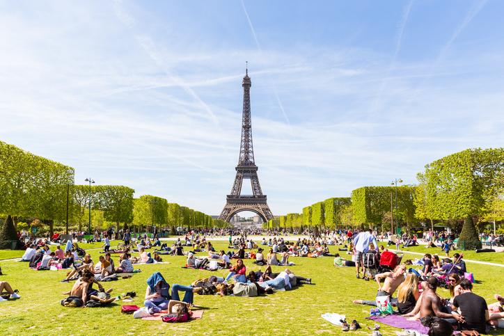 Paris, France - May 5, 2016: Lots of people relaxing and having fun on Champ de Mars with the Eiffel Tower on background on a sunny day.
