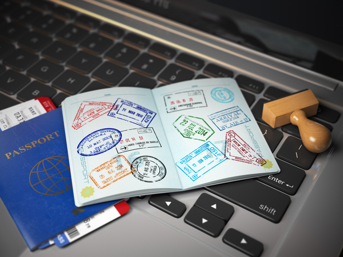 Visa online application concept. Open passport with visa stamps with airline boarding pass tickets and stamper on the computer keyboard. 3d illustration