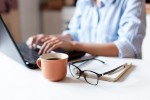 Do home office ao presencial: itens que vão facilitar a volta ao escritório Remote working from home. Freelancer workplace in kitchen with laptop, cup of coffee