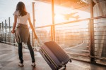 Voos na segunda quinzena de janeiro são até 38% mais baratos que no fim de dezembro Young woman pulling suitcase in airport terminal. Copy space