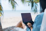 Woman using laptop and smartphone to work study in vacation cady at beach background. Business, financial, trade stock maket and social network concept.