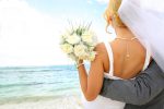 Groom holding his bride by the ocean