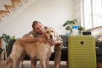 Descubra hotéis pet friendly em São Paulo retrato-de-um-jovem-abracando-seu-cachorro-indo-de-ferias-para-um-hotel-de-animais-de-estimacao-com-uma-mala-embalada