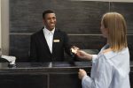 O que você precisa saber sobre o check-in digital em hotéis receptionist-elegant-suit-work-hours-with-customer